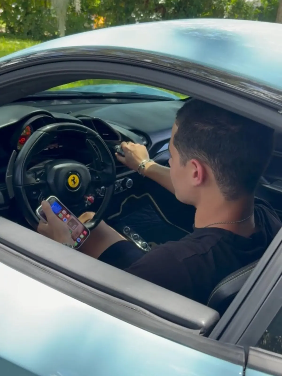 Zander in the driver's seat of a Ferrari, holding his phone