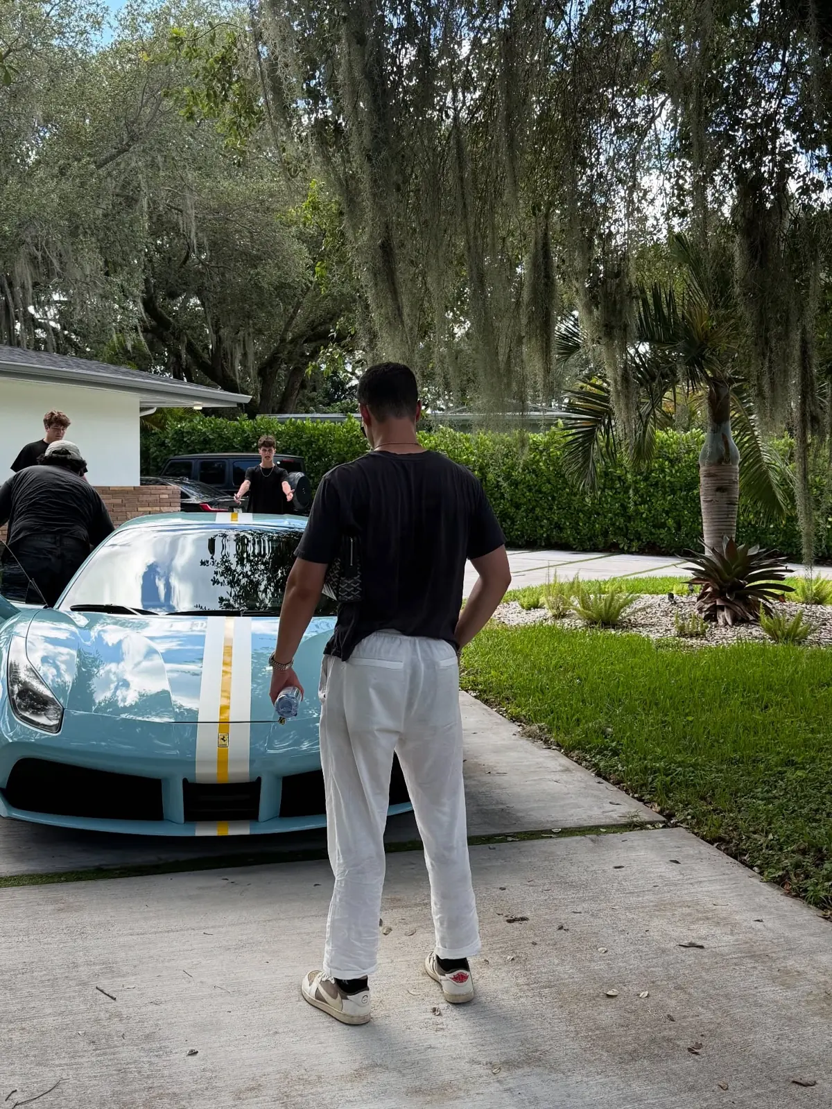 Zander standing beside a light blue Ferrari in a driveway