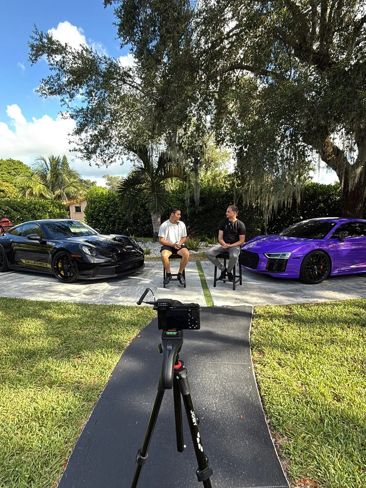 A camera set up to film an interview between two sports cars